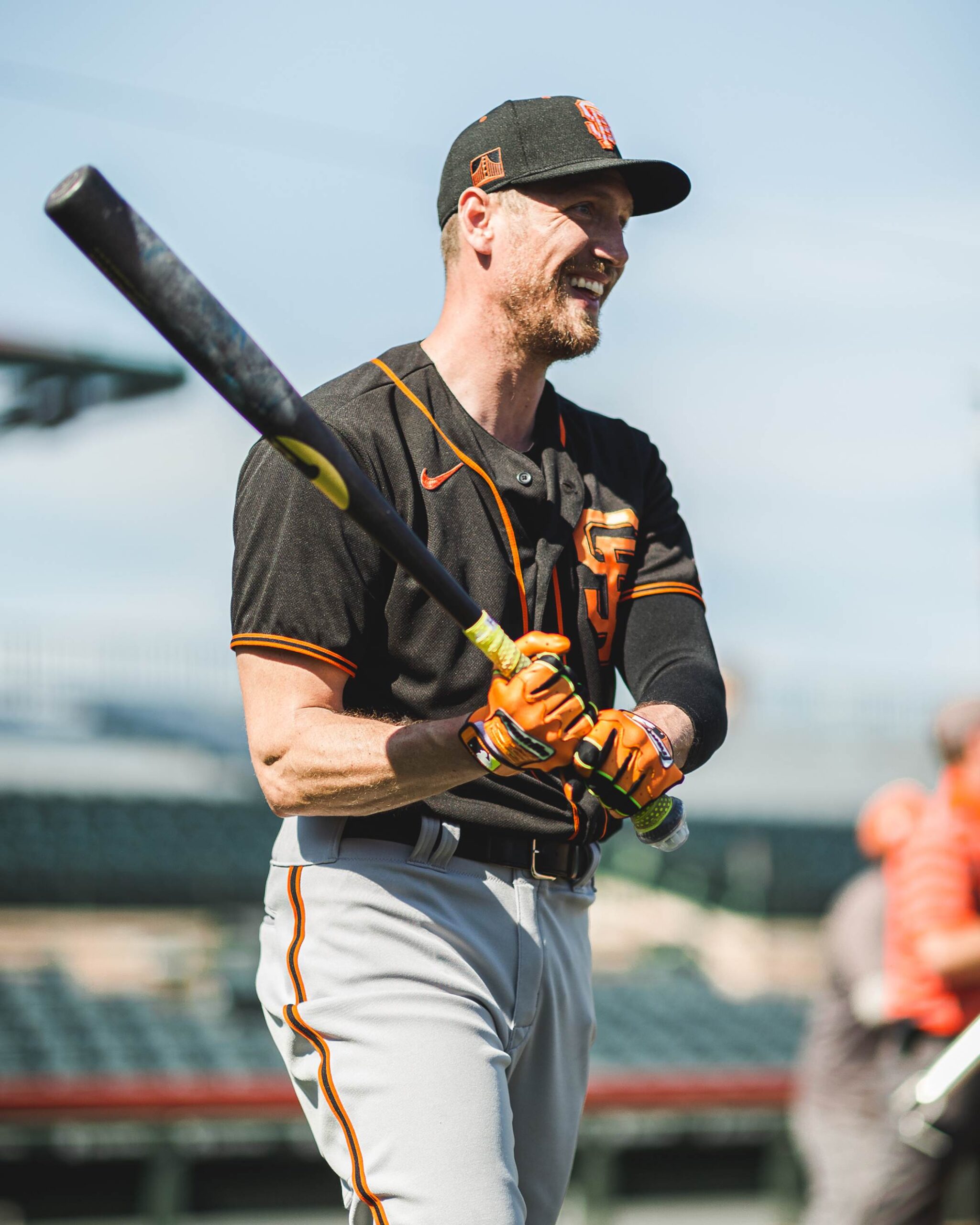 Close-up of a black and orange clad baseball player with a bat.