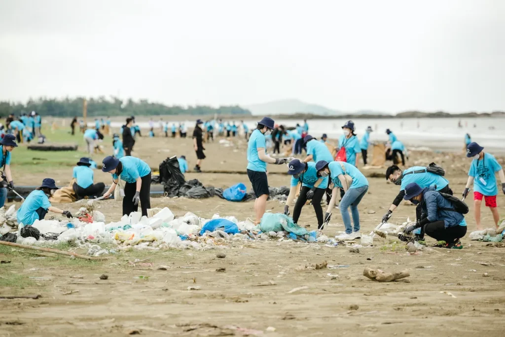 people picking up trash on the beach